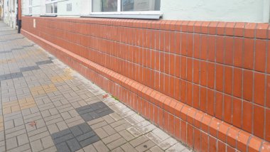 Rzeszow Polonya - 16 Kasım 2025: Bir şehir ortamında kentsel mimari ve modern tasarım sergilenen kaldırım boyunca turuncu tuğlalı bir duvara yakın plan.