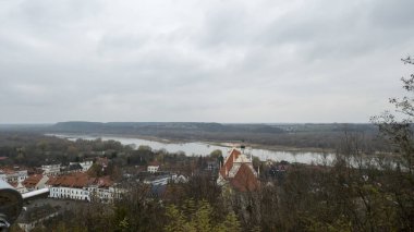 Kazimierz Dolny Polonya - 11 Kasım 2025: Vistula Nehri ve tarihi binaların yer aldığı Kazimierz Dolny 'nin doğal güzelliklerin sergilendiği bulutlu bir günde manzara.