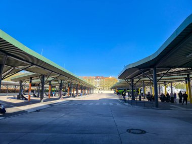 Berlin Almanya - 11 Nisan 2025: Geniş bir otobüs durağı, açık mavi gökyüzüne karşı geniş gölgeler altında sayısız bekleme alanı bulunan modern mimariye sahip.