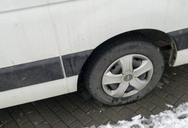 Rzeszow Polonya - 22 Kasım 2025: Kışın kaldırım taşlı bir sokakta park etmiş kirli bir lastiğin yakından görüntüsü kentsel taşımacılık zorlukları sergiliyor.
