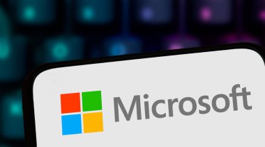 Varşova Polonya - 8 Kasım 2025: Microsoft logosunu bulanık bir klavye arka planında gösteren cep telefonu ekranının yakın çekimi. Modern teknoloji kavramı.
