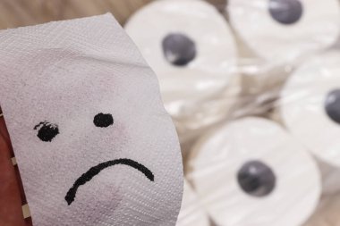 Bir parça tuvalet kağıdına çizilmiş üzgün bir yüzün yakın çekimi. Yumuşak dokular, yuvarlanmış tuvalet kağıdının beyaz zeminiyle hayal kırıklığını çağrıştıran duygular yaratıyor..