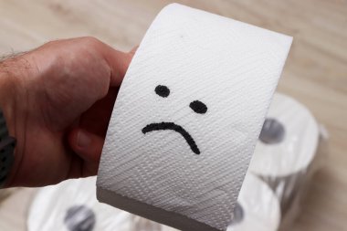 Üzüntülü bir yüz çizilmiş tuvalet kağıdını tutan bir el hayal kırıklığını ya da hayal kırıklığını simgeliyor..