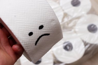 Üzücü bir yüz çizilmiş tuvalet kağıdı rulosunu tutan bir el. Görüntü, günlük banyo gereksinimlerini komik bir şekilde yakalıyor..