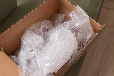 Nakliye veya depolama sırasında kırılgan eşyalara koruma sağlayan kabarcık ambalajlı yastık malzemesiyle dolu bir karton kutu. Paketleme çözümleri için ideal.