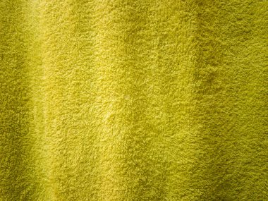 Yumuşak kabarık yüzeyini vurgulayan desenli sarı bir kumaşın yakın çekim görüntüsü. Arkaplan ya da tekstil tasarımları için ideal bu canlı renk sıcaklık ve tazelik ekler.