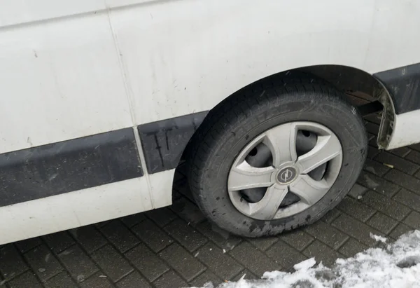 Rzeszow Polonya - 22 Kasım 2025: Kışın kaldırım taşlı bir sokakta park etmiş kirli bir lastiğin yakından görüntüsü kentsel taşımacılık zorlukları sergiliyor.