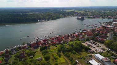 Mikolajki, Masuria 'nın göl boyunca canlı deniz manzaralı evleri, yemyeşil ve sakin manzaraya hayat veren yelkenli tekneleriyle çevrili hava manzarası..