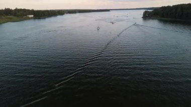 Mikolajki, Masuria, bereketli yeşillik ve manzaralarla çevrili sakin sularda gezinen teknelerle dolu göl aktivitelerini sergiliyor, yaz tatili için mükemmel..