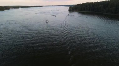 Mikolajki, Masuria 'daki sakin bir sahnede alacakaranlıkta sakin sularda yüzen tekneler görülüyor. Resmedilmeye değer manzara, kıyı şeridinde bereketli yeşillikler barındırır, yazın özünü yakalar..