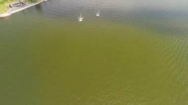 Mikolajki, Polonya, 9 Ağustos 2024: Sahil şeridi yakınlarındaki yeşil göl suyundan hızla geçen iki motorlu botun havadan çekimi