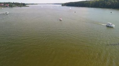 Mikolajki, Polonya, 9 Ağustos 2024: Çeşitli boyutlarda teknelerle sularda sakin bir yaz günü, yemyeşil manzaralar arasında yol alarak, dinlenme ve rahatlama manzarası yaratıyor.