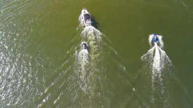 Mikolajki, Polonya, 9 Ağustos 2024: Parlak güneş ışığı altında dinamik hareket ve eğlence faaliyetleri sergileyen, yemyeşil bir gölde üç su aracı geziniyor. Sahne, yaz gezilerinin neşesini su üzerinde yakalıyor.