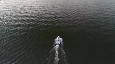 Mikolajki, Polonya, 9 Ağustos 2024: Akşamları karanlık sularda yüzen bir sürat teknesinin hava görüntüsü. Tekne hızla hareket ederken bir iz bırakır. Sahnenin dinamik ve dinamik doğasını gözler önüne serer.