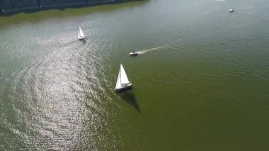 Mikolajki, Polonya, 9 Ağustos 2024: Uzaktaki liman ve liman binaları ile gölde seyir halindeki yelkenlilerin insansız hava aracı görüntüsü