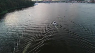 Mikolajki, Polonya, 9 Ağustos 2024: Masuria 'da bir gölün üzerinde, sakin sularda yüzen teknelerin yer aldığı, bölgenin doğal güzelliklerini gösteren pitoresk bir akşam manzarası