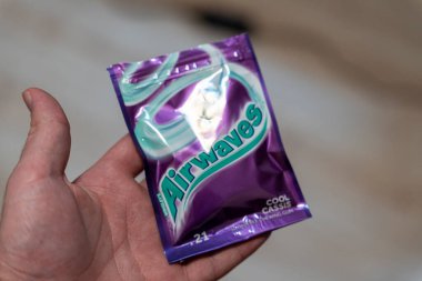 Varşova Polonya - 5 Aralık 2025: Cool Cassis aromalı bir sakız paketini tutan bir elin yakın çekimi. Canlı mor ambalaj bulanık bir arka planla çelişiyor.