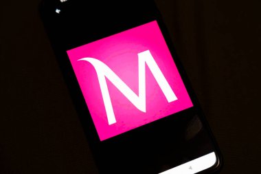 Varşova Polonya - 4 Aralık 2025: M harfli canlı pembe bir logo gösteren akıllı telefon ekranının yakından görüntüsü logo markalaşma ve pazarlama potansiyelini gösteriyor..