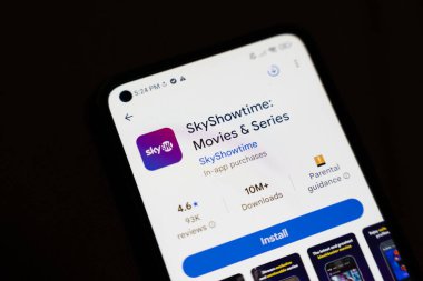 Varşova Polonya - 4 Aralık 2025: SkyShowtime uygulamasını gösteren bir akıllı telefon ekranının yakın çekimi filmler ve diziler hakkında detaylar ve istatistikler indiriliyor.