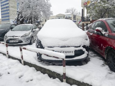Rzeszow Polonya - 22 Kasım 2025: Karla kaplı araçlar bir şehir parkına park edildi. Bir kış sahnesinde kar yağışının şehir ortamları üzerindeki etkisi gözler önüne seriliyor.