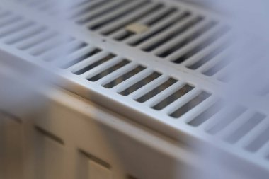 Görünür ısıtma elementleri olan beyaz bir radyatörün yakın görüntüsü. Çekim, yüzeyin dokusunu ve işlevselliğini gösteren detaylı bir perspektifini yakalıyor..