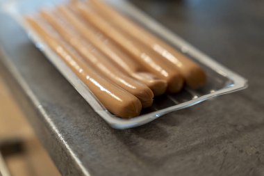 Pack of sausages on a kitchen counter showcasing fresh ingredients ready for meal preparation. Ideal for culinary food blogs or advertisements related to cooking.
