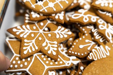 Çok güzel dekore edilmiş zencefilli kurabiyelerin yakın çekimi. Karmaşık beyaz krema desenleri festival için mükemmel. Pazarlama ve tatil temaları için ideal.