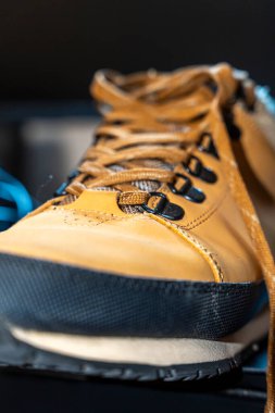 Siyah lastik tabanlı, engebeli sarı bir tırmanma ayakkabısının yakın çekimi. Görüntü, açık hava maceraları ve tırmanma faaliyetleri için ideal bağlama sistemini ve sağlam materyali vurgular.