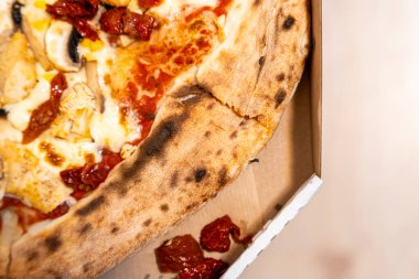 Kurutulmuş domatesli lezzetli pizza ve paket servis kutusunda sunulan tavuk. Yemek severler ve canlı renkler ve dokular gösteren aşçılar için mükemmel..