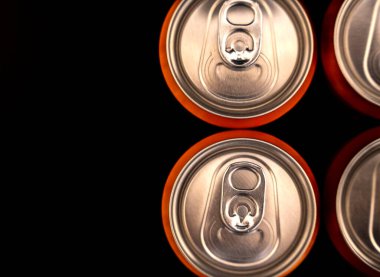 Metalik yüzey ve turuncu jantları koyu arka planda barındıran istiflenmiş içecek kutularının yakın çekim görüntüsü. Reklam ve ürün promosyonları için mükemmel..