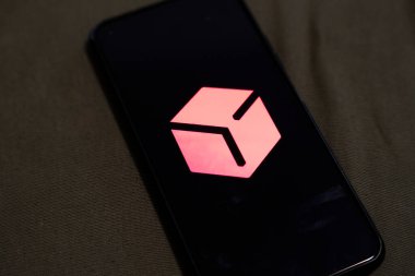 Varşova Polonya - 4 Aralık 2025: Pembenin tonlarında geometrik tasarımı olan modern bir logoyu gösteren akıllı telefon ekranının yakın çekimi. Teknoloji ve marka bağlamları için ideal.