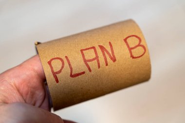 Üzerinde el yazısı plan B olan karton bir tüp tutan bir el. Bu resim iş ve kişisel planlamada kavramsal temalar için uygun esneklik ve strateji önerir.