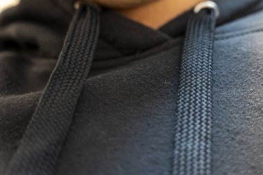 Koyu mavi kapüşonlu bir kapüşonlunun yakın çekimi. Dokusunu ve detaylarını gösteriyor. Kumaş ve çekiş tellerine odaklanmak günlük kıyafet tasarımı ve moda tercihleri hakkında içgörü kazandırır.