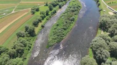 Görünür akıntı ve yeşil adalar arasında akan örülmüş bir nehrin havadan görünüşü kırsal bir yaz manzarasında doğal desenler oluşturur.