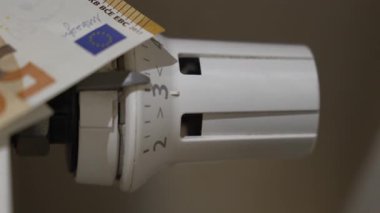 Isıtma giderlerini sembolize eden bir ev radyatörüne konulan avro banknotlarına yakından bakmak ve iç iç piyasalarda artan enerji maliyetlerine bakmak