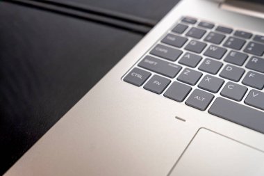 Tarafsız bir çalışma alanındaki modern bir dizüstü bilgisayar klavyesinin yakın plan görüntüsü. Siyah bir arkaplana karşı metal ve plastik dokular sergileniyor. Teknoloji sektörü veya eğitim temaları için ideal.