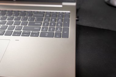 Modern teknolojinin sergilendiği karanlık bir masa yüzeyindeki dizüstü bilgisayarın klavyesinin yakın çekimi. İş temaları için ideal çalışma ortamları ve dijital yenilikçi imajlar.