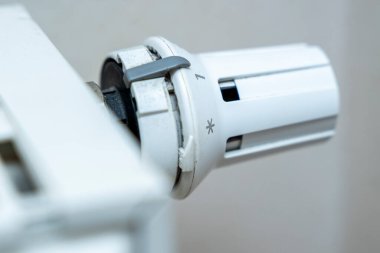 Beyaz radyatör termostatının yakın plan görüntüsü 1 sayısını ve bir yıldız işaretini gösteriyor. Ev ısıtma konuları için ideal DIY projeleri veya enerji verimliliği tartışmaları.