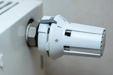 Çeşitli sıcaklık ayarlarını gösteren beyaz bir radyatör termostat kapağının yakın çekimi. İç tasarım ve bakımda ev ısıtma ve enerji verimliliği kavramları için ideal.