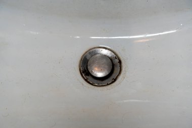 Ev tesisatında yıpranma ve yıpranma ve yıpranma kenarlarında pas ve kir bulunan kirli banyo lavabosunun yakın görüntüsü. Temizlik veya ev geliştirme temaları için kullanışlı.