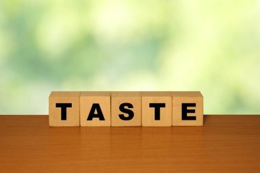 Tahta küplerin ahşap bir yüzeyde sergilenmesi yumuşak, bulanık yeşil bir zemin ile lezzet yemek deneyimlerinin ve duyusal algının temaları vurgulanıyor..