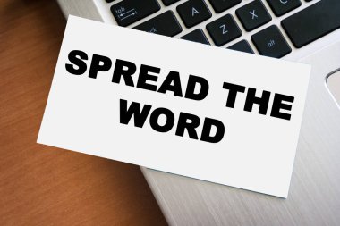 Kelimeyi dizüstü bilgisayarın klavyesine yerleştirilmiş beyaz bir kağıda dağıt cümlesini içeren el yazısı bir not. Bu ifade, dijital bağlamda iletişim ve bilgi paylaşımını ifade eder.