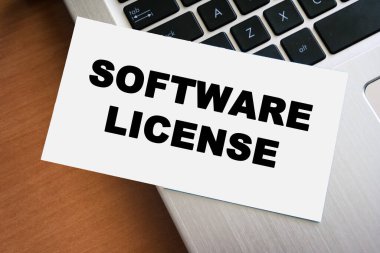 Bir dizüstü bilgisayarın klavyesine yerleştirilen ve yazılım kullanım hakları ve yönetmeliklere uyma hakkında bilgi taşıyan beyaz bir sayfa üzerinde el yazısıyla yazılmış metin SOFTWARE LICENSE.