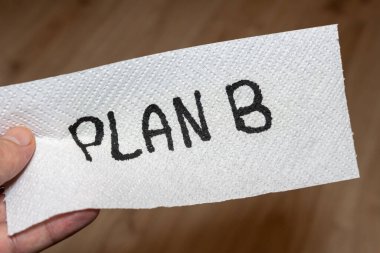 El yazısıyla yazılmış bir not, elinde kağıt havlu olan bir B Planı diyor. Bu resim, problem çözme ve karar verme de dahil olmak üzere çeşitli bağlamlarda alternatif çözümleri ve seçenekleri simgeler.