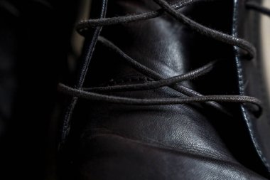 Karmaşık dantelli siyah deri ayakkabının yakın plan görüntüsü, ayrıntılı tasarım işçiliği ve stili. Moda reklamı ve perakende satış bağlamları için ideal.