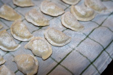 Leh pierogisinin geleneksel hazırlıklarını gösteren un tozlu bir bez parçasına yerleştirilmiş ev yapımı hamur tatlısı. Yemek blogları, yemek pişirme dergileri ya da mutfak reklamları için ideal..