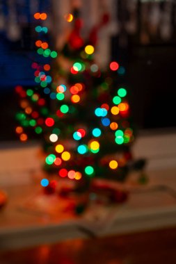 Süslü bir Noel ağacının bulanık bir görüntüsü. Renkli ışıklar parıldıyor. Bayram sezonu boyunca kapalı bir ortamda neşeli bir atmosfer yaratıyor..