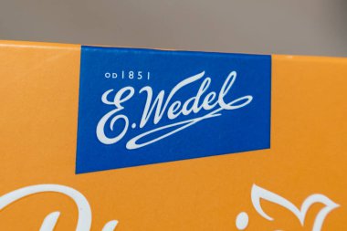 Varşova Polonya - 16 Aralık 2025: Turuncu ambalaj üzerindeki E.Wedel logosunun yakın çekimi. Marka, 1851 'den beri kaliteli bir deneyimi olan zengin çikolata ürünleriyle tanınır..