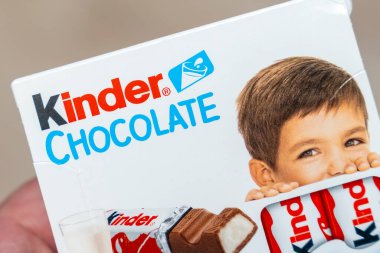 Varşova Polonya - 16 Aralık 2025: Arkadan gizlice gözetleyen bir çocuğu gösteren Kinder Çikolata paketinin yakın çekimi. Ürün vurguları çocuklar için uygun nitelikleri ele alıyor.