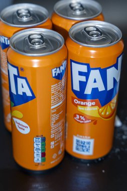Varşova Polonya - 16 Aralık 2025: Fanta portakallı soda kutularının yakın çekimleri, canlı turuncu renkler ve ferahlatıcı bir içecek seçeneğini gösteren markalar sergileniyor.
